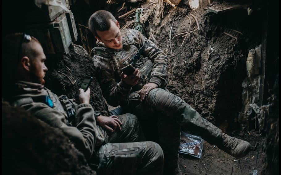 A navigator, with the call sign Actor, and the drone operator Sapsan rest while looking at their phones in a forward bunker position on the southern front line near Robotyne Sept. 14. 