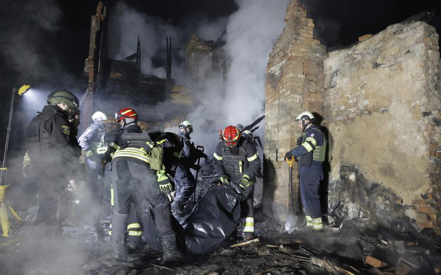 Ukrainian firefighters looking through rubble.