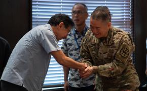 A U.S. soldier in uniform shakes hands with a Japanese official.