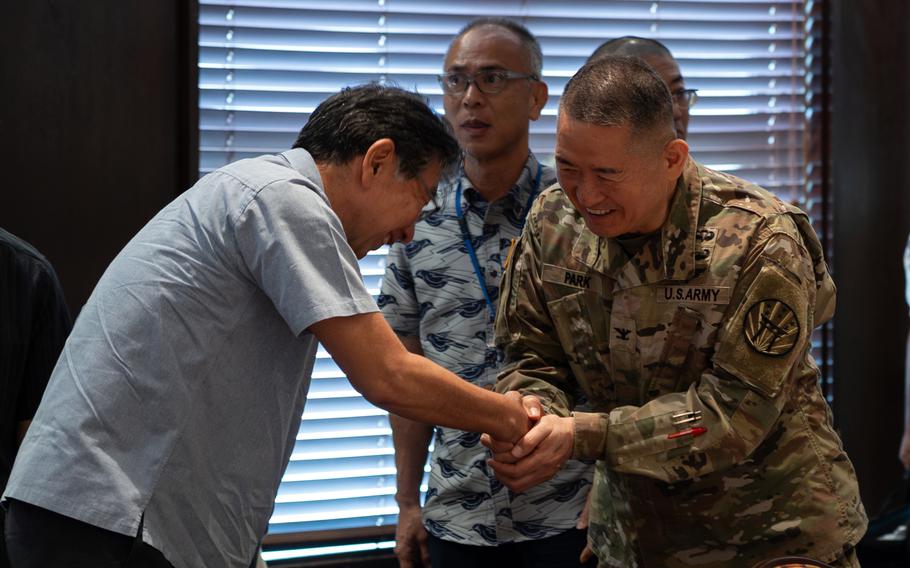 A U.S. soldier in uniform shakes hands with a Japanese official.