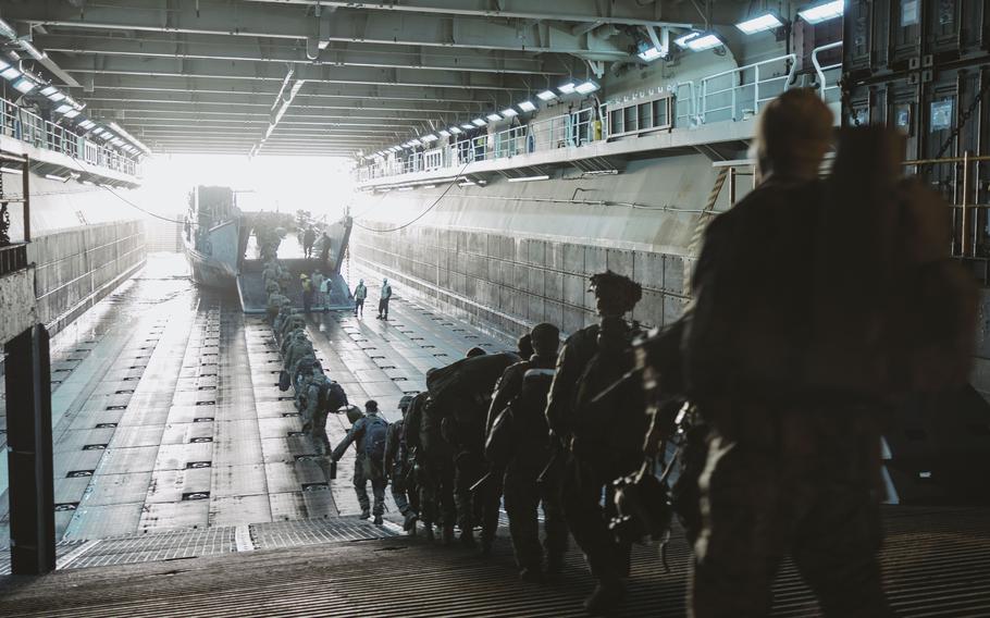 A long line of troops boarding a smaller vessel inside a larger ship.