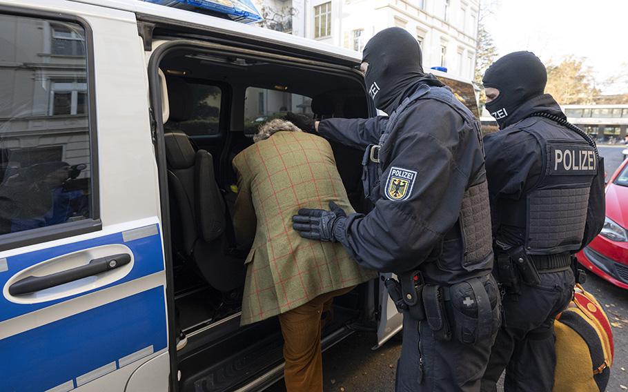 Masked police officers lead an arrested suspect Heinrich XIII Prince Reuss, left, to a police vehicle during a raid against so-called ‘Reich citizens’ in Frankfurt, Germany, on Dec. 7, 2022. 