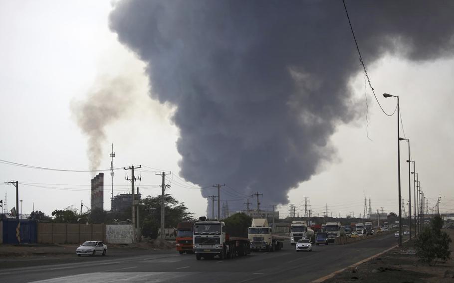 Smoke rises in background from an explosion at an Iranian port.