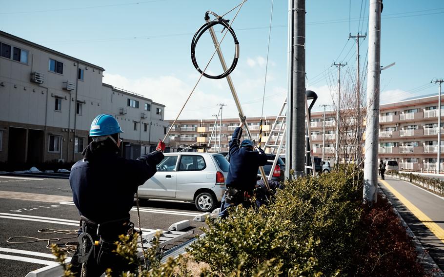 Construction workers raise power lines at a public housing site in Ishinomaki, Japan, Feb. 10, 2016.