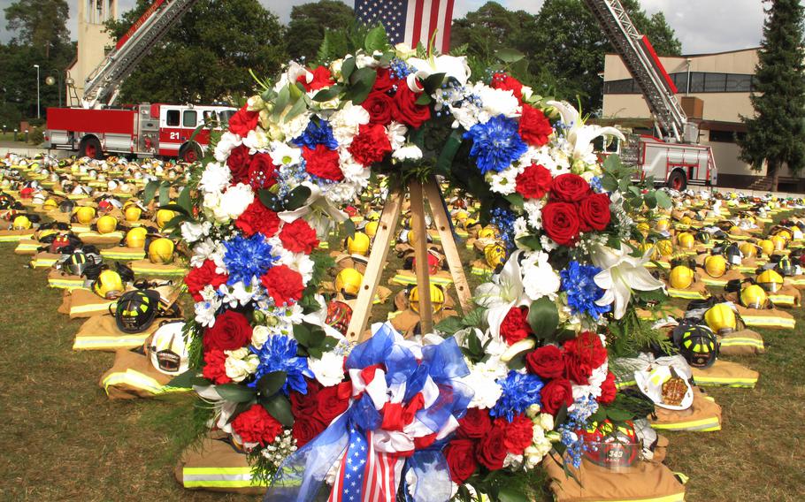 A wreath laid by service members at Ramstein Air Base sits in front of hundreds of firefighters' helmets and protective gear during a ceremony on Sept. 10, 2021, to mark the 20th anniversary of the 9/11 attacks on the U.S. 