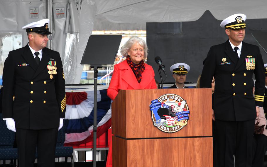 A lady speaks at a podium with two sailors next to her