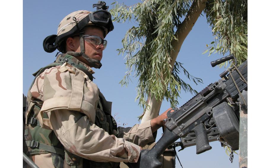 A member of Company C, 4th Battalion, 31st Infantry Regiment waits atop an armored Humvee as his colleagues talked to townspeople in Saba al Boor, Iraq.