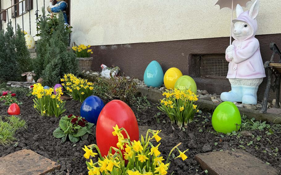 Daffodils, egg yard decorations and a bunny statue with an umbrella are on display.