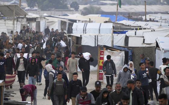People walking next to tents with white bags of food.
