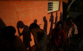 The shadows of Haitian migrants are cast on a wall as they wait to receive food at a tourist campground in Sierra Morena, in the Villa Clara province of Cuba, Wednesday, May 25, 2022. A vessel carrying more than 800 Haitians trying to reach the United States wound up instead on the coast of central Cuba, government news media said Wednesday. (AP Photo Ramon Espinosa)