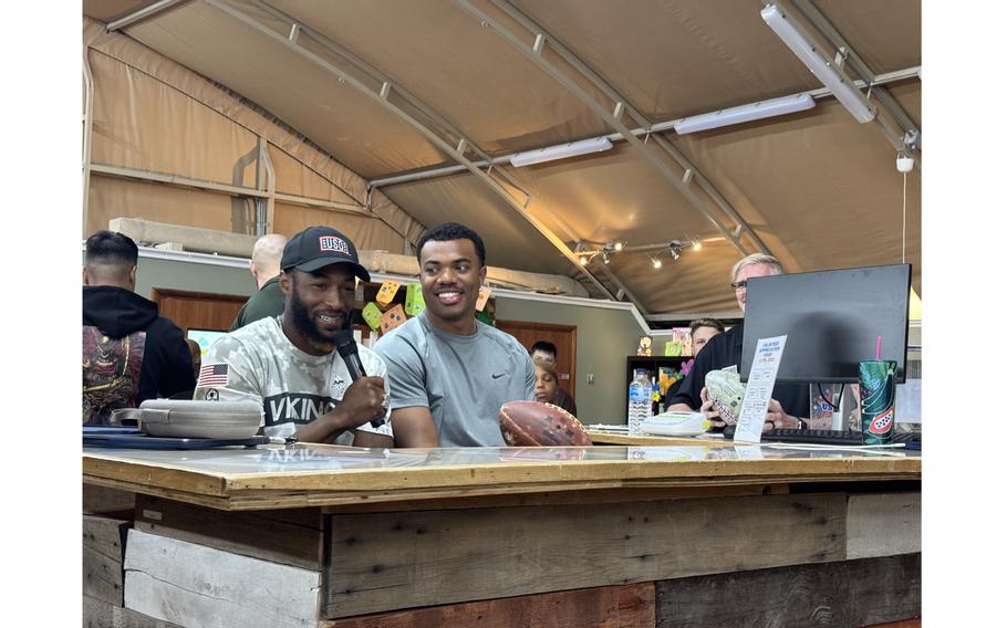 Two men smile as they sit together behind a desk