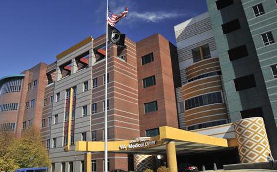 Brown, gray and white buildings are seen on a sunny day with the U.S. flag raised.