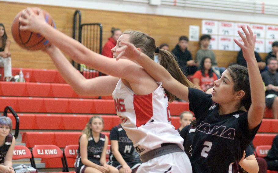 E.J. King's Madylyn O'Neill comes down with a rebound against Zama's Isabella Rivera Munoz during Friday's DODEA-Japan girls basketball season-opening game. The Cobras won 69-33.