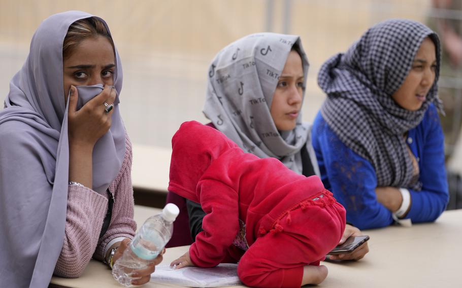 Recently evacuated Afghan women sit beside a baby at Ramstein Air Base, Germany, Tuesday, Aug. 24, 2021.