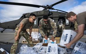 National Guard personnel load food and water into a Black Hawk helicopter.
