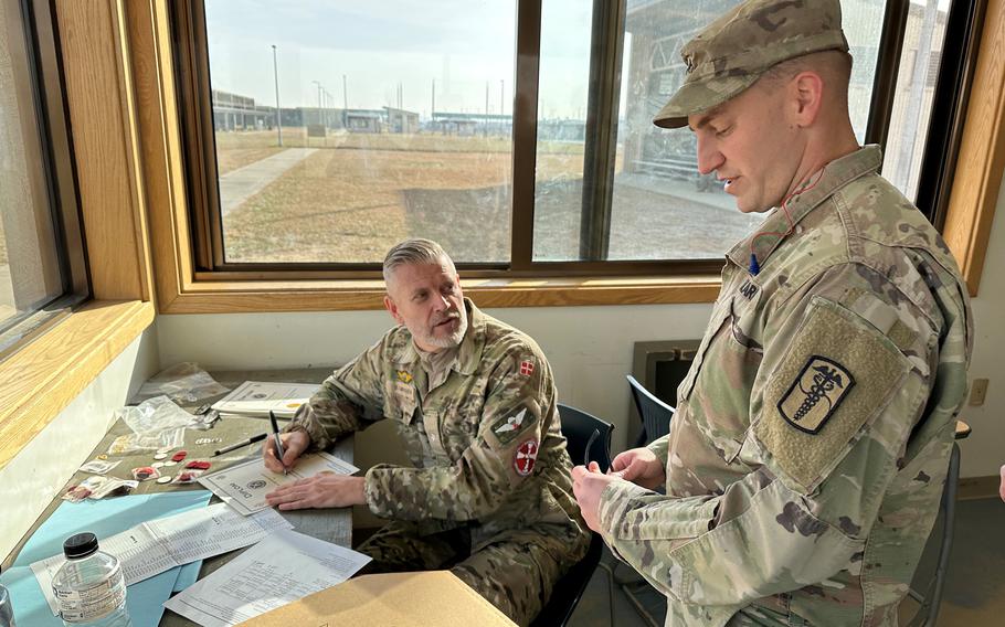 Danish Army Maj. Soeren Madsen, left, scores a target belonging to a U.S. soldier, right, who is competing for a Danish Marksmanship Badge at Camp Humphreys, South Korea, Monday, Dec. 12, 2022.