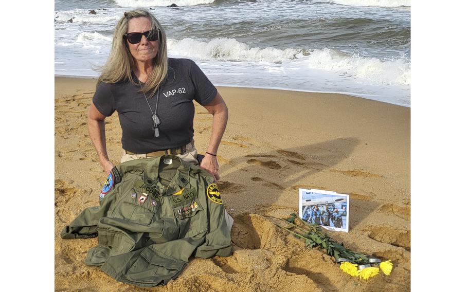A woman sits on a beach with a jacket