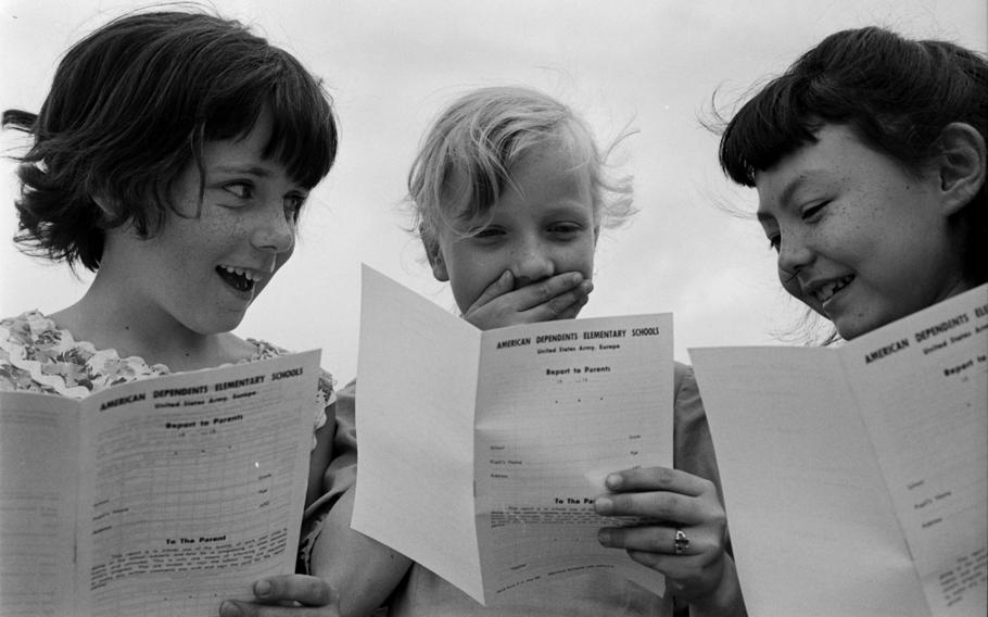 Three children looking at folded pieces of paper.