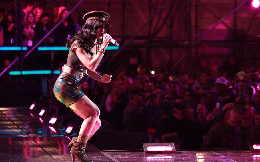 Katy Perry, wearing a retro military uniform inspired outfit, sings during a concert.