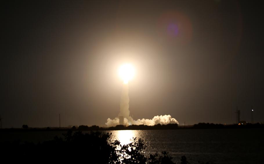 A bright light in the middle of a dark sky caps off a large plume of smoke.