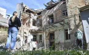 People look at a damaged residential building following Russian air attack in Lviv, Ukraine, Saturday, July 12, 2025. (AP Photo/Mykola Tys)