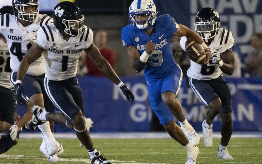 Air Force quarterback Zac Larrier (9) runs downfield for a first down against Utah State safeties Anthony Switzer (1) and Ike Larsen (6) during the first half of an NCAA college football game in Air Force Academy, Colo., Friday, Sept. 15, 2023.