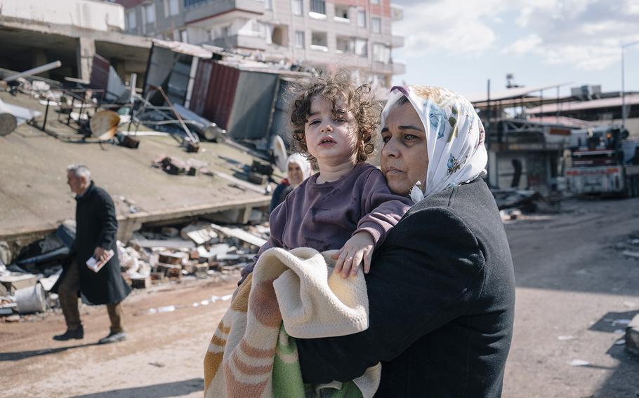 A woman holds a small child crying for her father in Nurdagi, Turkey, on Feb. 7, 2023.