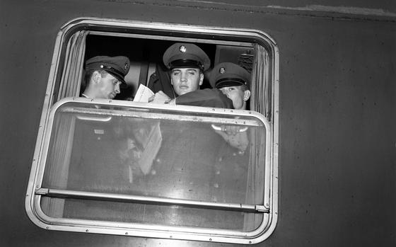 Pvt Elvis Presley holds a Stars and Stripes newspaper as he  looks from a troop train window on his departure from Bremerhaven, Germany, to duty at Friedberg, near Frankfurt. 