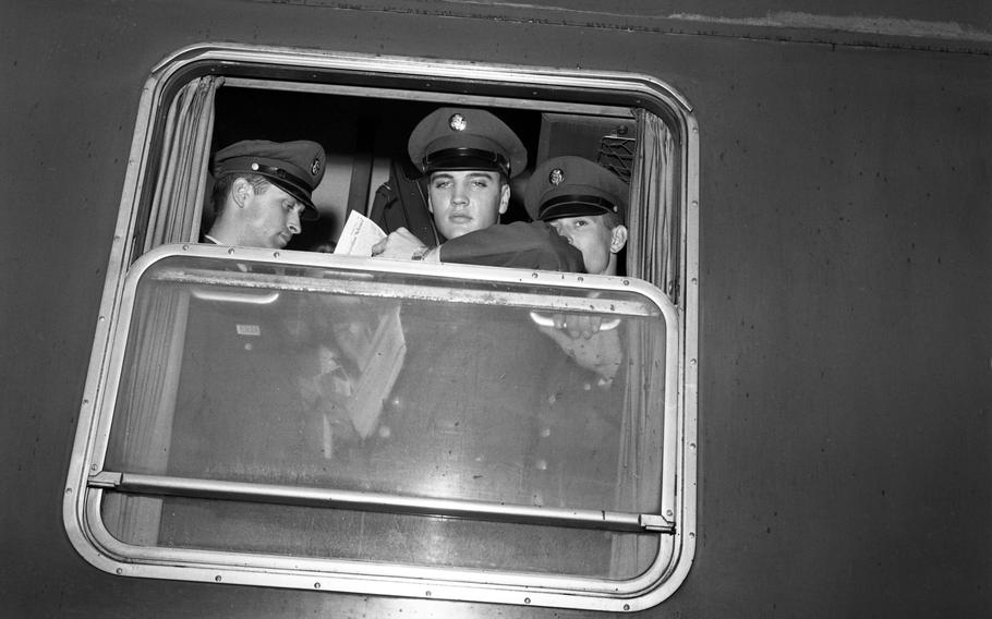 Pvt. Elvis Presley holds a Stars and Stripes newspaper as he  looks from a troop train window on his departure from Bremerhaven, Germany, to duty at Friedberg, near Frankfurt. 