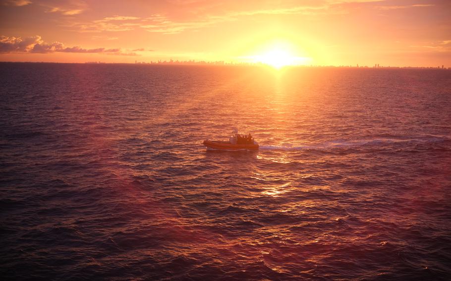 A boat on the water with an orange sunset in the background.