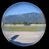 A mountain and military helicopter are seen through a circular window.