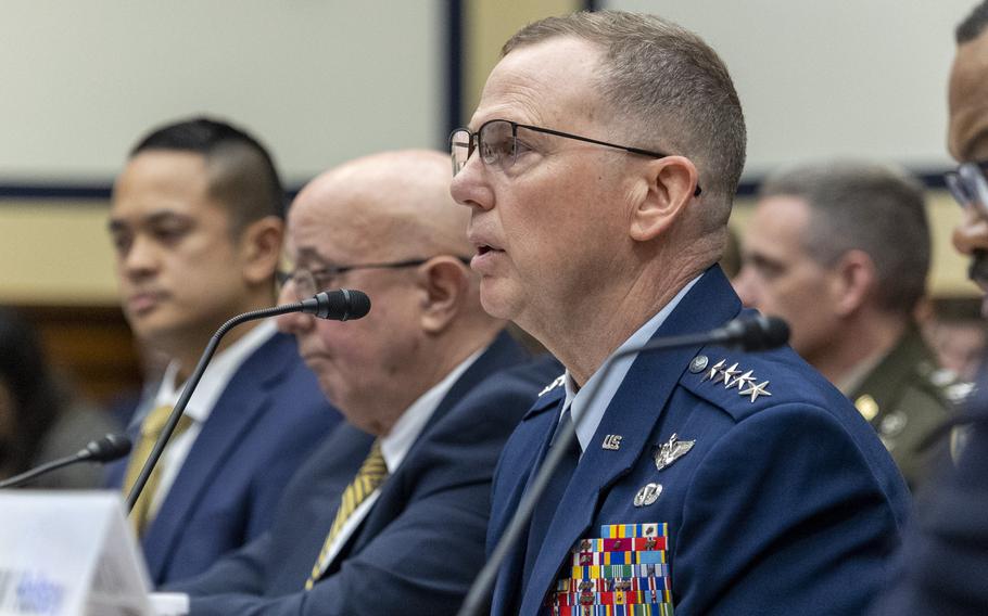 An Air Force officer in dress uniform speaks into a microphone in a congressional hearing room.