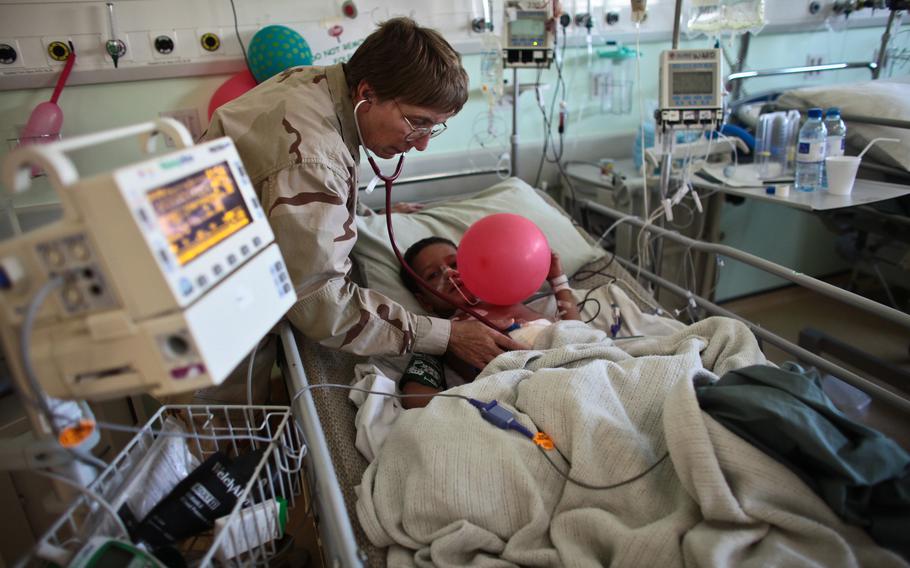 A boy takes a balloon in a hospital bed