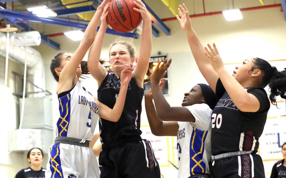 Zama's Lorelei Holt comes down with a rebound between Yokota's Erica Haas and Beverly Gardner as teammate Deborah McClendon looks to help during Friday's DODEA-Japan/Kanto Plain girls basketball game. The Trojans won 30-29 in overtime.