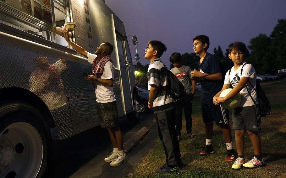 Afghan boys wait for French fries at a food cart at a park on Aug. 19 in Sacramento. Some were born in Afghanistan. (Carolyn Cole/Los Angeles Times/TNS)