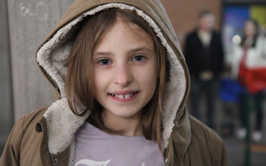 An elementary schooler in a hoodie smiles at the camera.