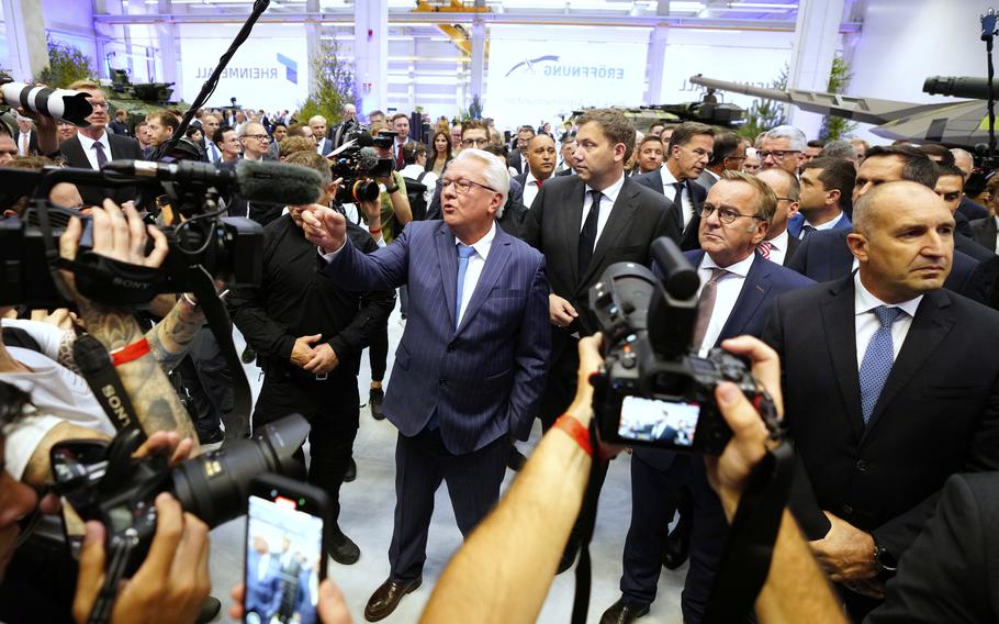 A crowd, with media microphones, gather in the factory.