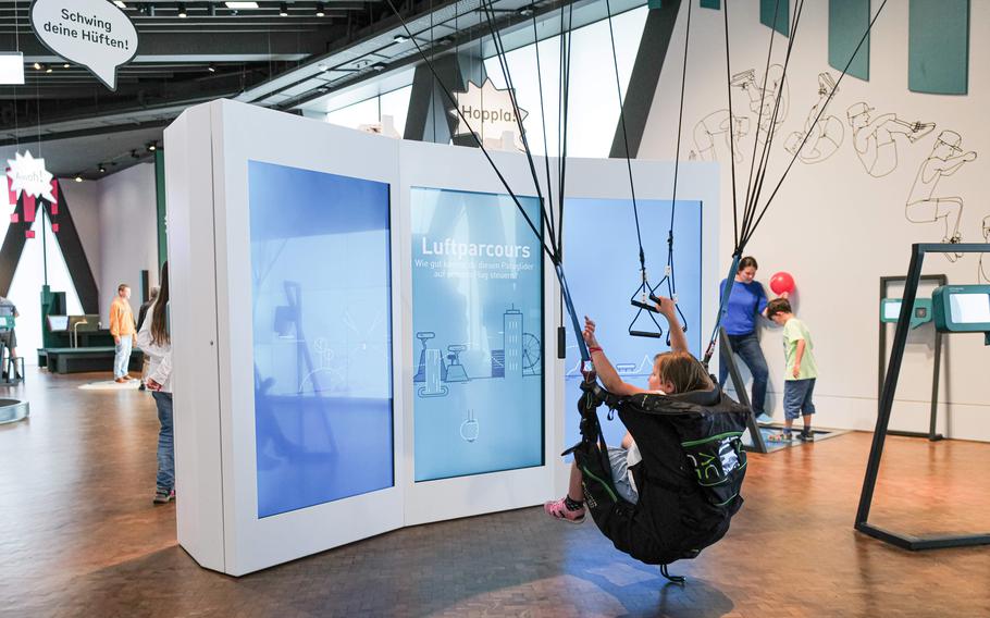 A girl tries the air parcour hang glider station at the Experimenta Science Center, learning about aerodynamics and balance in a fun and interactive way.