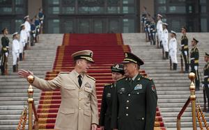 The U.S. Chairman of the Joint Chiefs of Staff gestures one arm to the side while speaking with a general of the Chinese army.
