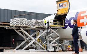 Workers unload a FedEx Express cargo plane carrying one million eight-ounce bottles of Nestlé's Gerber Good Start Extensive HA infant formula as a Secret Service agent stands watch at Dulles International Airport in Dulles, Virginia, on May 25, 2022. 