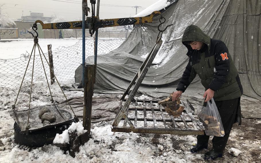 A few sticks of firewood, weighed on a scale and sold for half a dollar, are all that the family of this boy and many others can afford to heat their homes for one night during this snowy winter in Kabul, Afghanistan, on Jan. 4, 2022. 