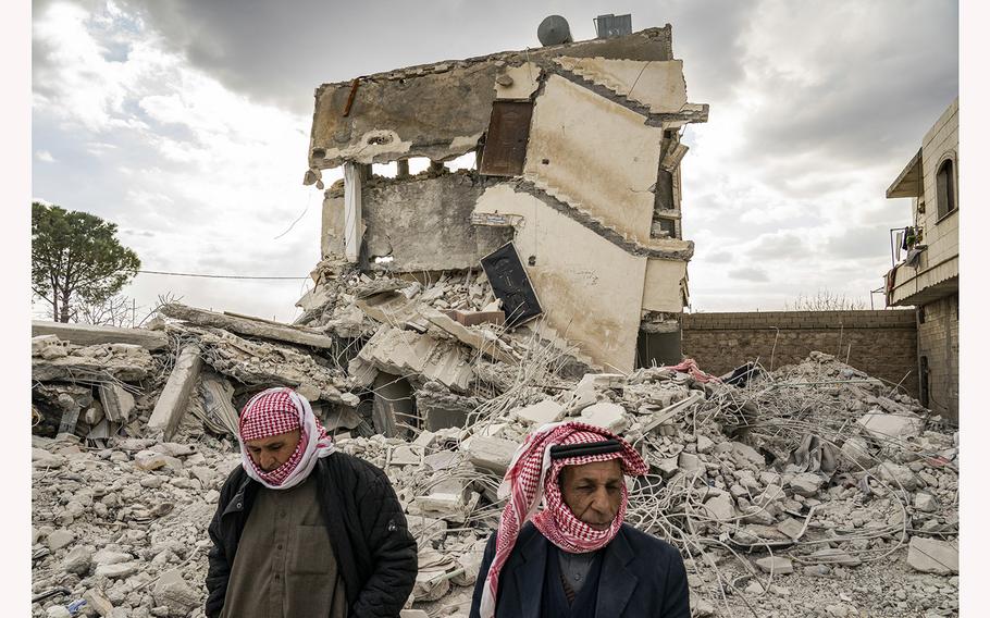 Residents walk past the rubble of homes and buildings on their street in Jinderis, Syria, on Feb. 10, 2023.