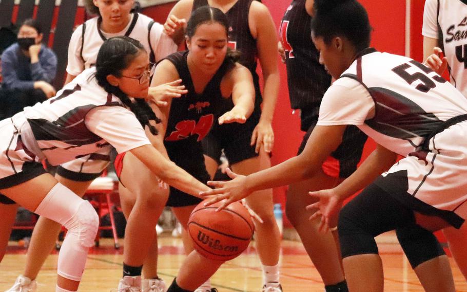 Matthew C. Perry's Elieza Cuaco and Kaiden Bradley and Nile C. Kinnick's Kotone turner scramble for the ball  during Saturday's DODEA-Japan girls basketball game. The Red Devils won 38-19.