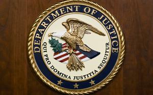 The seal of the Department of Justice is displayed on a wooden background.