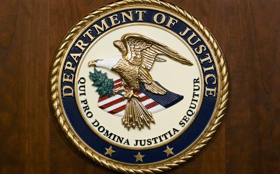 The seal of the Department of Justice is displayed on a wooden background.