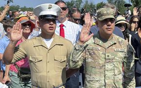 A marine and Army service members raising their right hand during a naturalization ceremony.