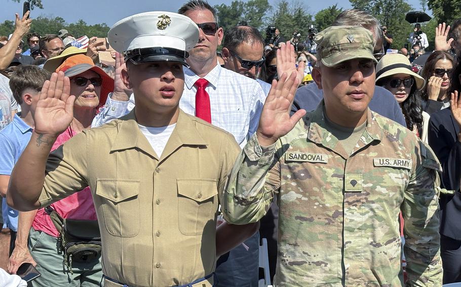 A marine and Army service members raising their right hand during a naturalization ceremony.