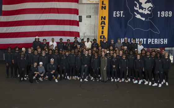 231224-N-PV534-1040 SAN DIEGO (Dec. 24, 2023) University of Southern California Trojans football team poses for a photo during an open ship tour aboard the Nimitz-class aircraft carrier USS Abraham Lincoln (CVN 72) prior to the 2023 Holiday Bowl. Abraham Lincoln is currently moored pierside at Naval Air Station North Island. (U.S. Navy photo by Mass Communication Specialist 2nd Class Victoria Armstrong)