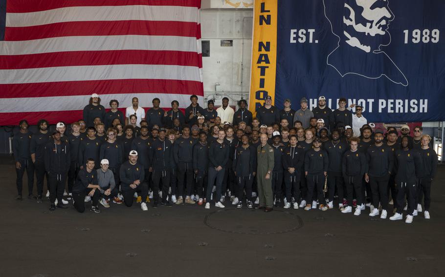 USC Trojans football players pose for a photo Dec. 24, 2023, during an open ship tour aboard the Nimitz-class aircraft carrier USS Abraham Lincoln prior to the 2023 Holiday Bowl. Abraham Lincoln is currently moored pierside at Naval Air Station North Island.