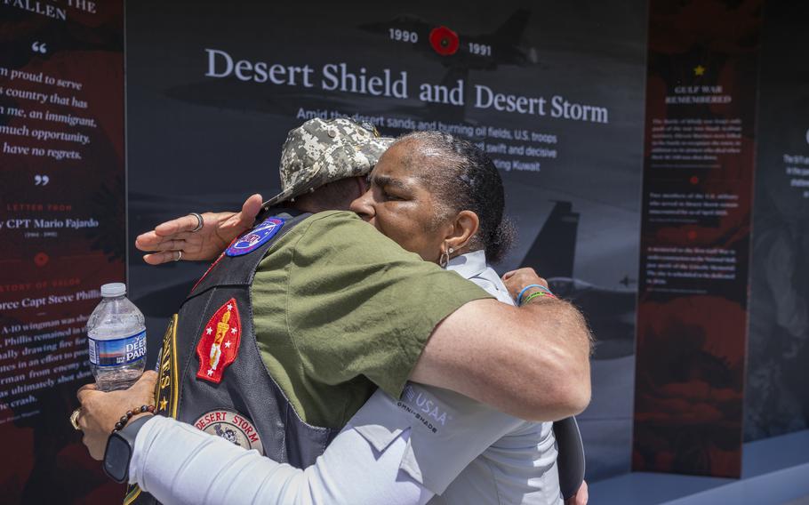 Two people embrace before a display about Operations Desert Shield and Desert Storm.